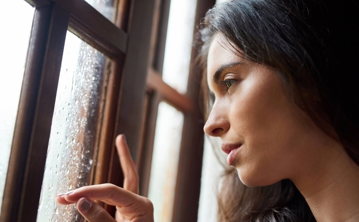 Untitled-38 A woman looks out a window covered in raindrops.