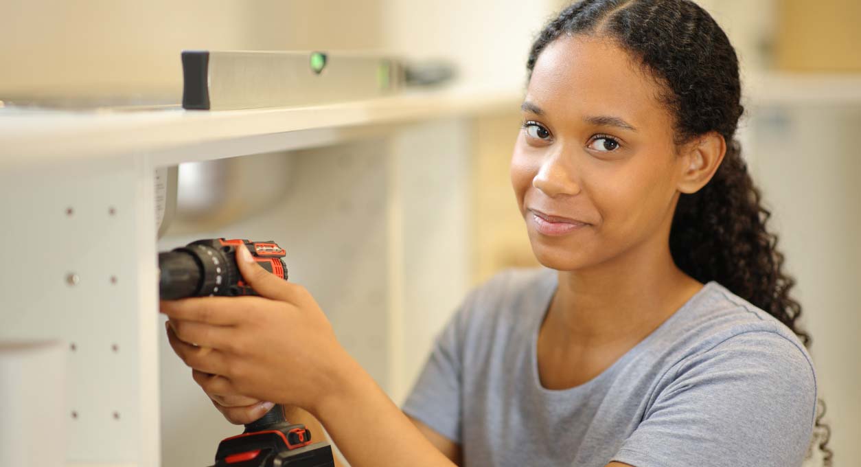 An African American woman holds a hand drill.