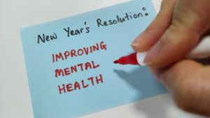 New Year's Resolution: Improving Mental Health -- is written on a blue note card.