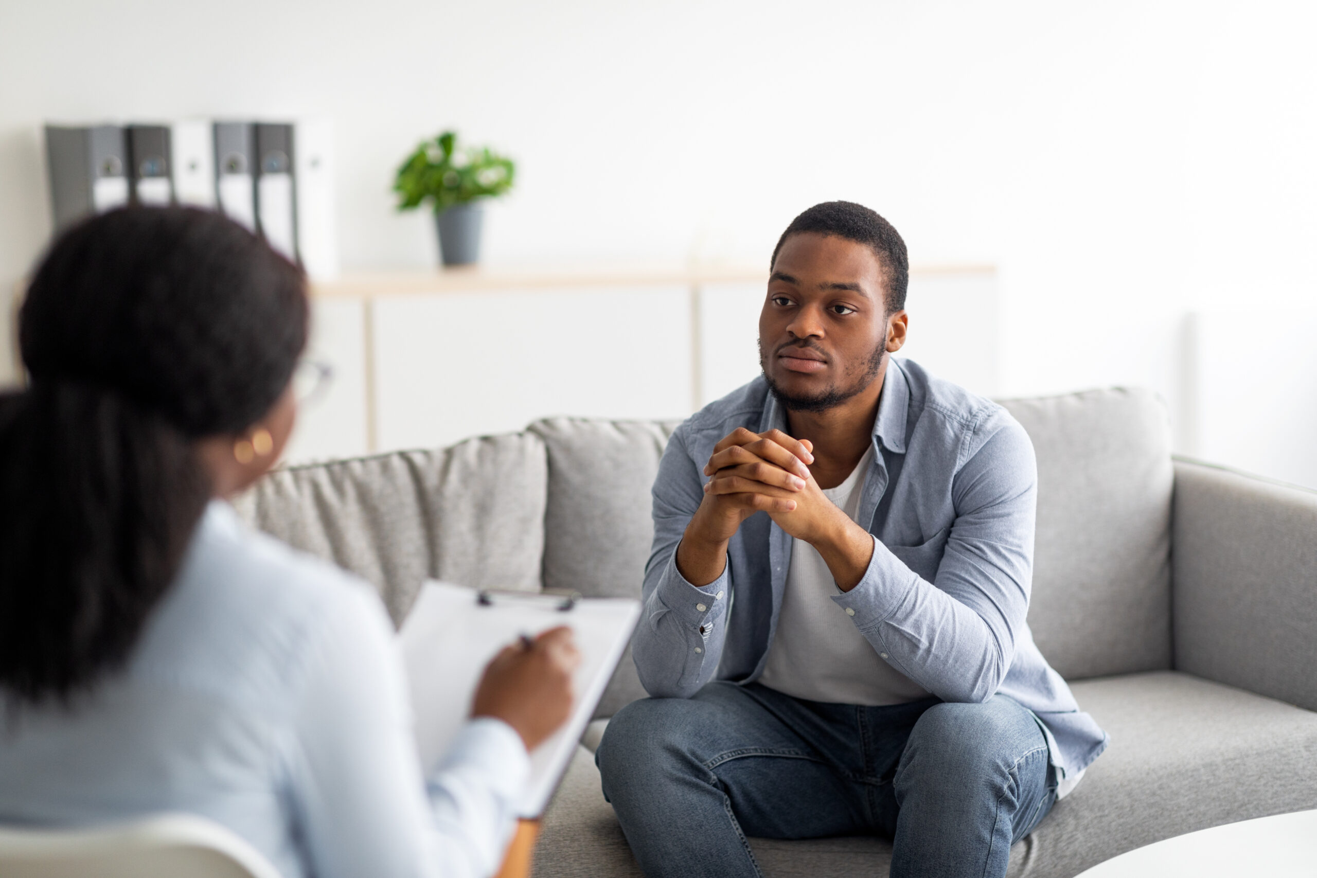 Male client listening to a therapist during a mental health consultation.