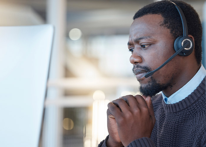 A male therapist chats with a client on a telehealth call.