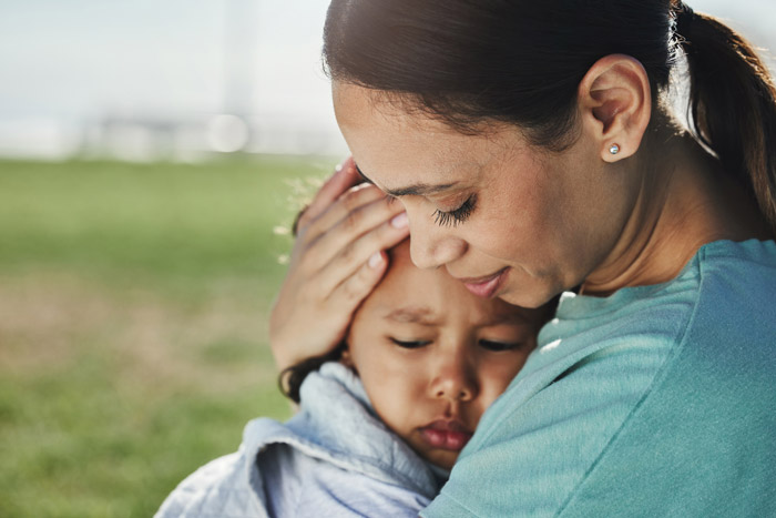 An adult caregiver comforts a small child.